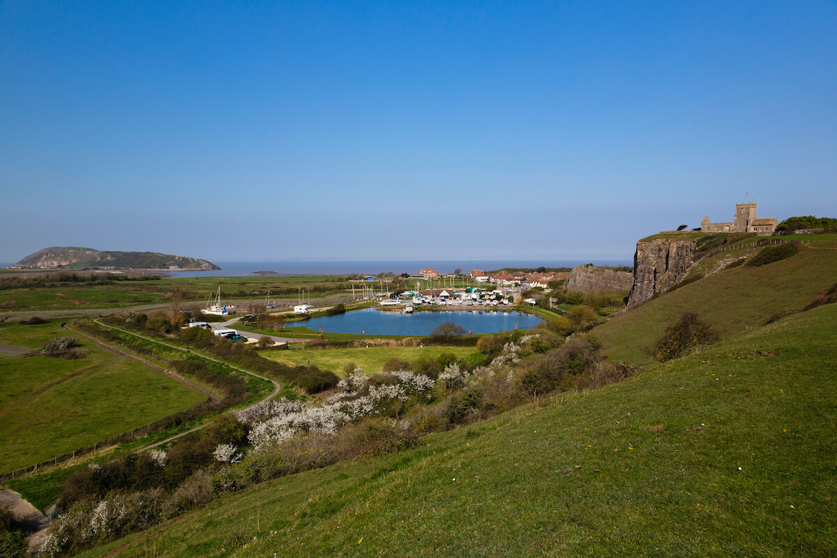View from a hill of a small lake and the sea in the background